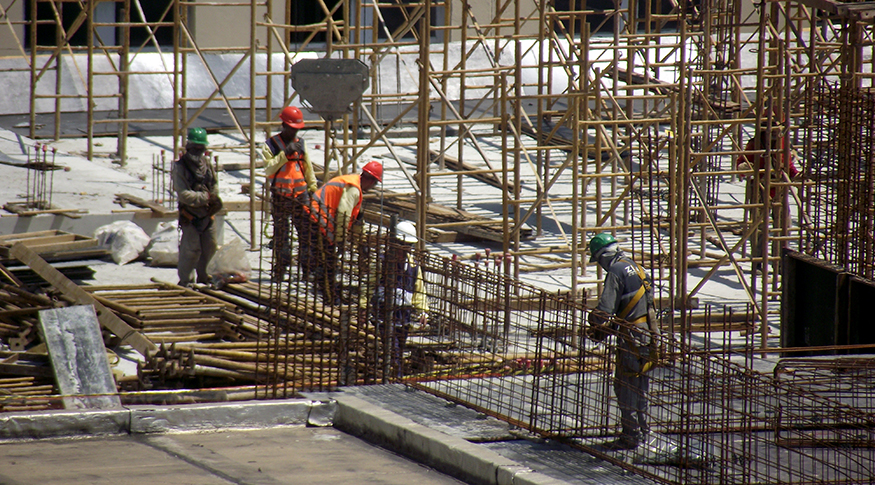 #PraCegoVer foto de operários entre vigas em uma construção