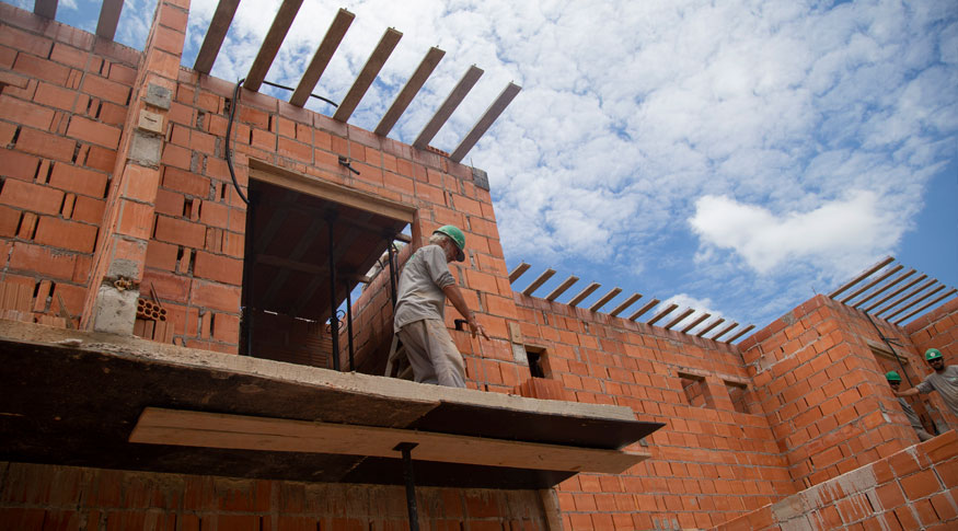 #PraCegoVer A foto mostra a parte de cima de uma obra em andamento, ainda na fase de colocação de telhas