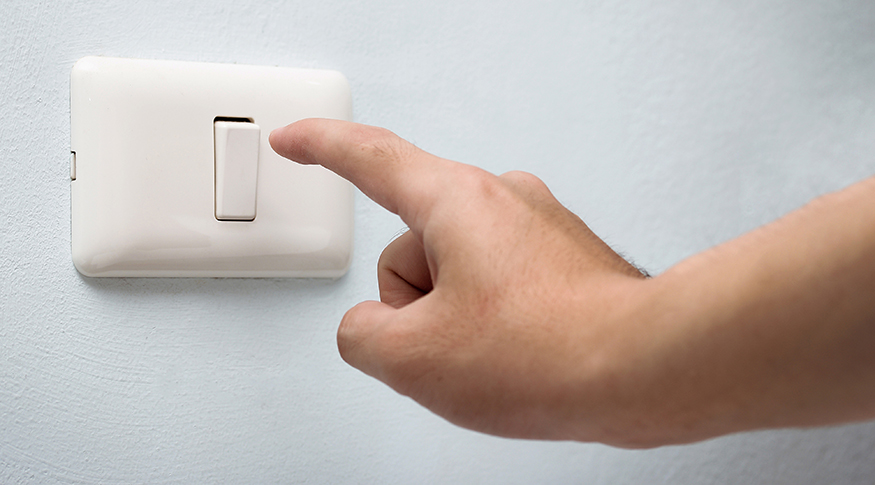 #PraTodosVerem A foto mostra uma mão apertando um interruptor na parede.