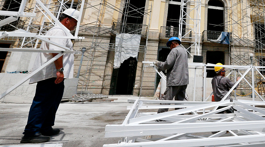 #PraCegoVer a foto mostra operários de construção e a fachada de um prédio