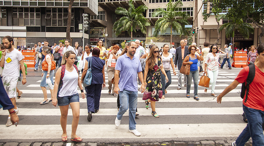 #PraCegoVer A foto mostra vária pessoas atravessando uma rua movimentada no Centro do Rio de Janeiro