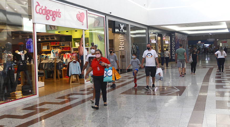 #PraCegoVer Pessoas caminhando no corredor de um shopping, com máscaras para se protegerem do COVID-19