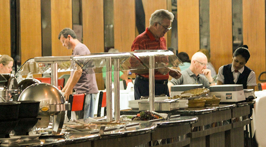 #PraCego Ver A foto mostra um senhor escolhendo comida num restaurante de comida a quilo