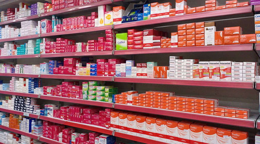 #PraCegoVer a foto mostra embalagens de remédios em prateleiras de farmácia 