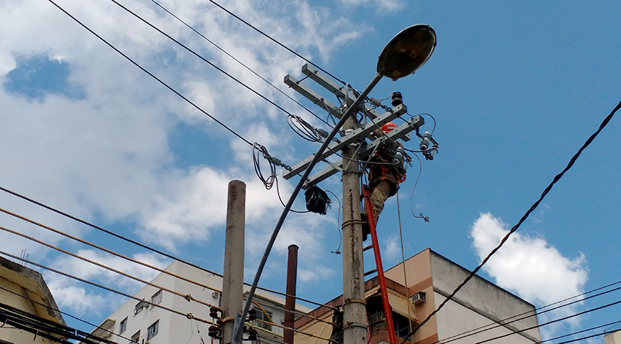 #PraCegoVer A foto mostra um operário trabalhando no alto de um poste de rede elétrica