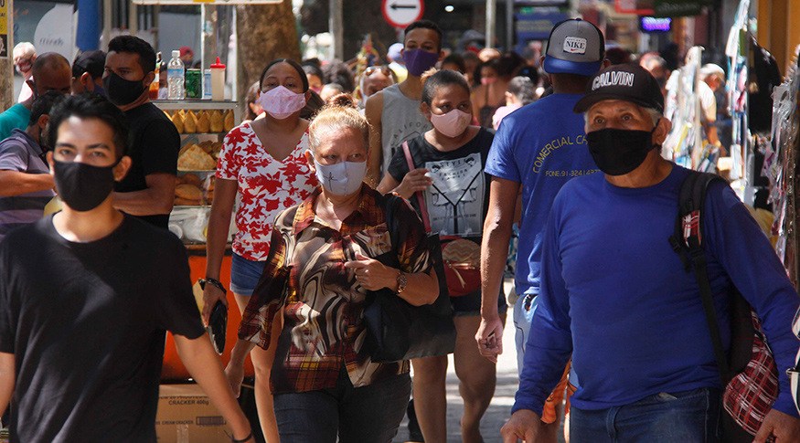 #PraCegoVer Pessoas de máscara andando na rua