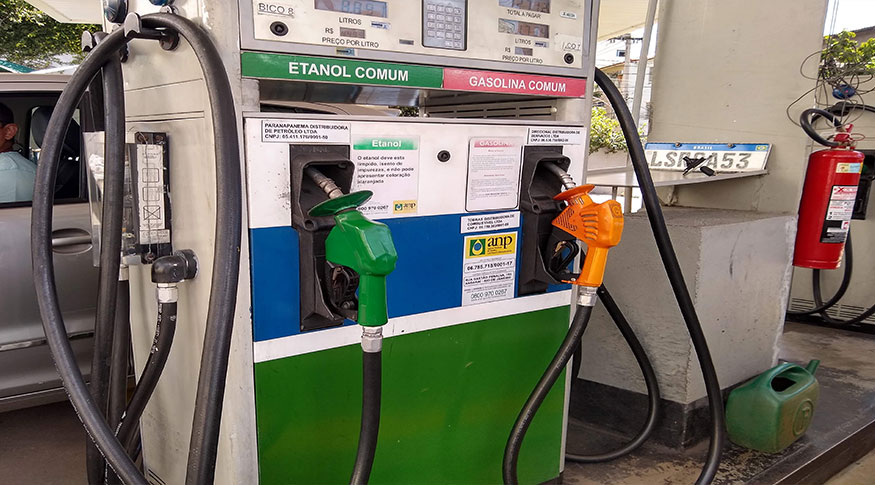 #PraCegoVer A foto mostra em primeiro plano duas bombas de gasolina, nas cores verde e branco.