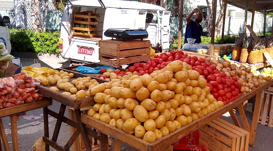 #PraCegoVer A foto uma feira livre, em primeiro plano uma barraca com batatas e tomates.