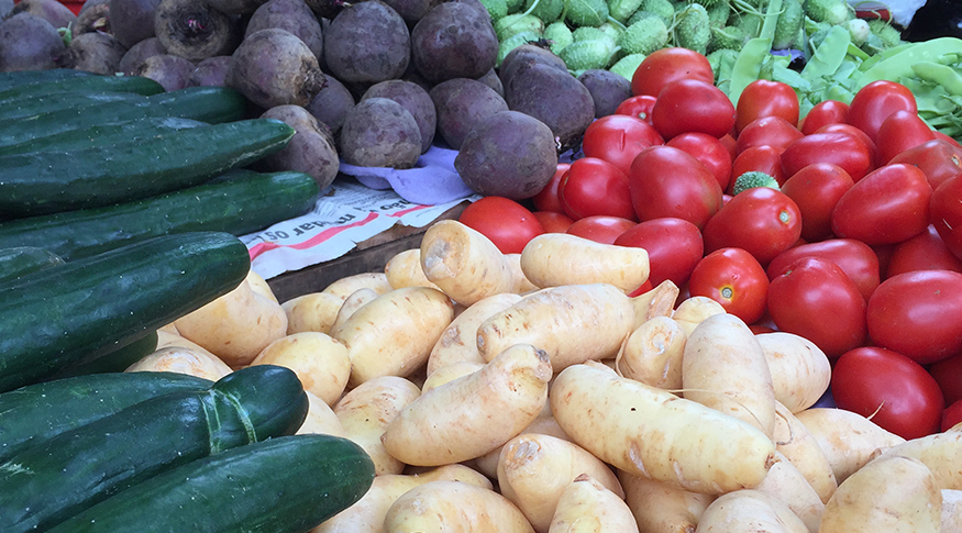 #PraCegoVer A foto mostra uma gôndola de supermercado com pepinos, batatas e tomates.