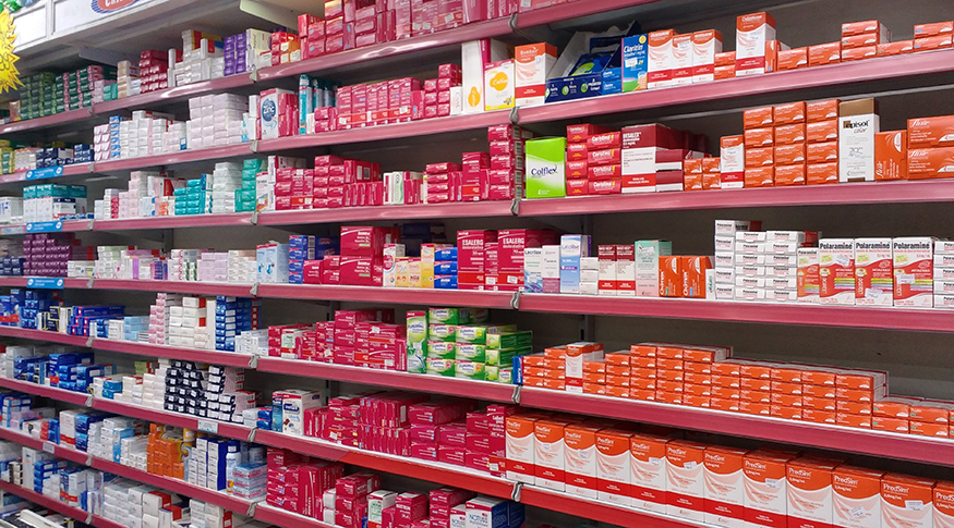 #PraCegoVer De foto toont schappen in een apotheek, vol dozen met medicijnen.