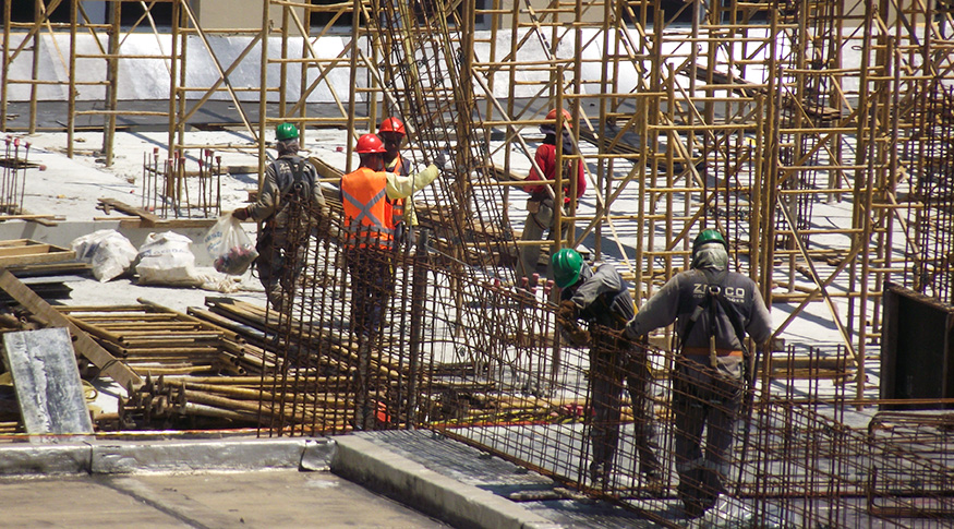 #PraCegoVer A foto mostra alguns operários montando uma estrutura metálica.
