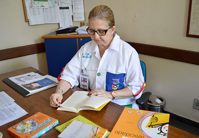 #PraCegoVer Regina Porto e os livros que usa na contação de histórias para crianças e adolescentes