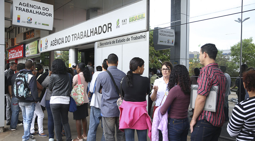 #PraCegoVer A foto mostra uma fila de pessoas procurando emprego, em frente à Agência do Trabalhador
