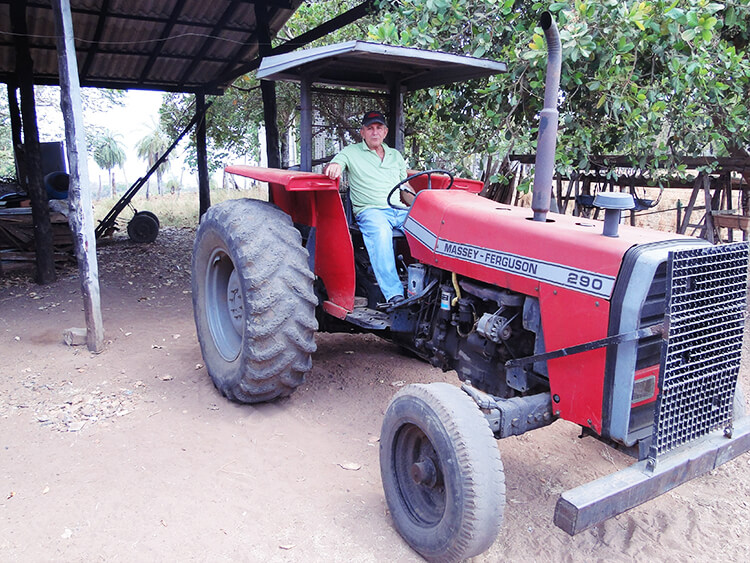 #PraCegoVer proprietário rural senhor edimar sentado em trator vermelho