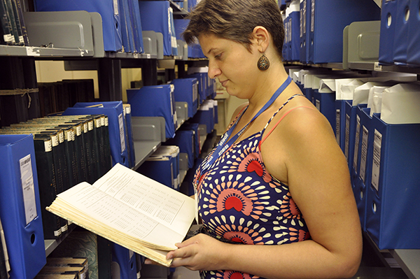 #praCegoVer Suzane Lima Conceição, funcionária da biblioteca, analisa o acervo