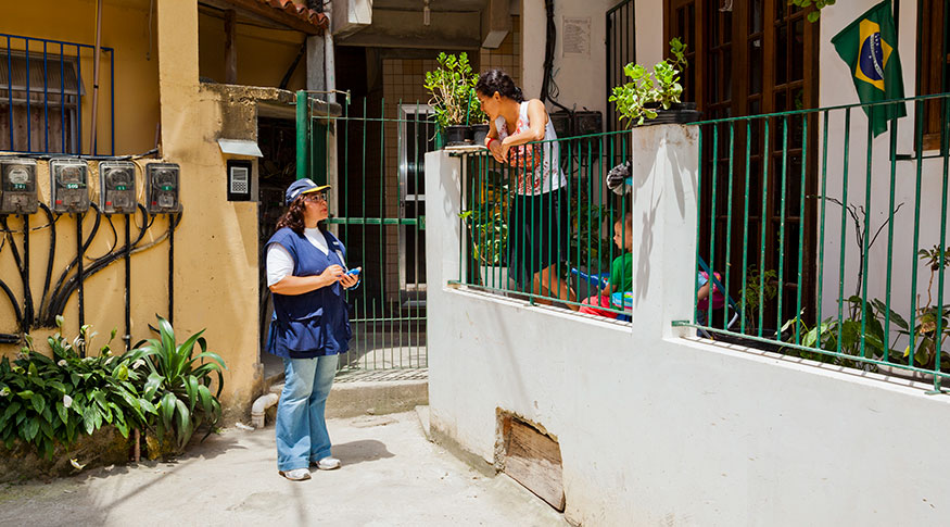 #PraCegoVer censitário entrevistando um morador no portão de casa